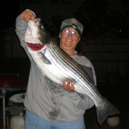 Rox holding a 34" striper caught in her fishing kayak