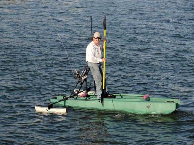 fly fisherman standing on top of his kayak, sight fishing